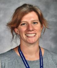 Headshot of a white woman in her 30s with dark blonde hair that is tied back, wearing a grey shirt with a FCHS ID lanyard.